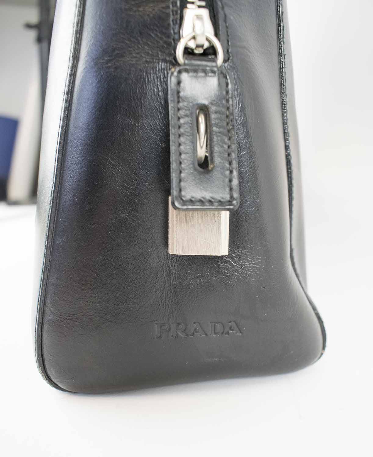 PRADA VINTAGE BAGS, one black leather with double top fabric handles,  padlock and keys 37cm x 27cm H x 13cm and the other leather with brass tone  studs decorations and hardware, top